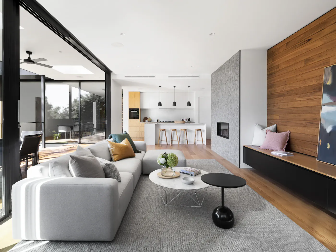 Open-plan living room with a timber feature wall and a low grey sofa