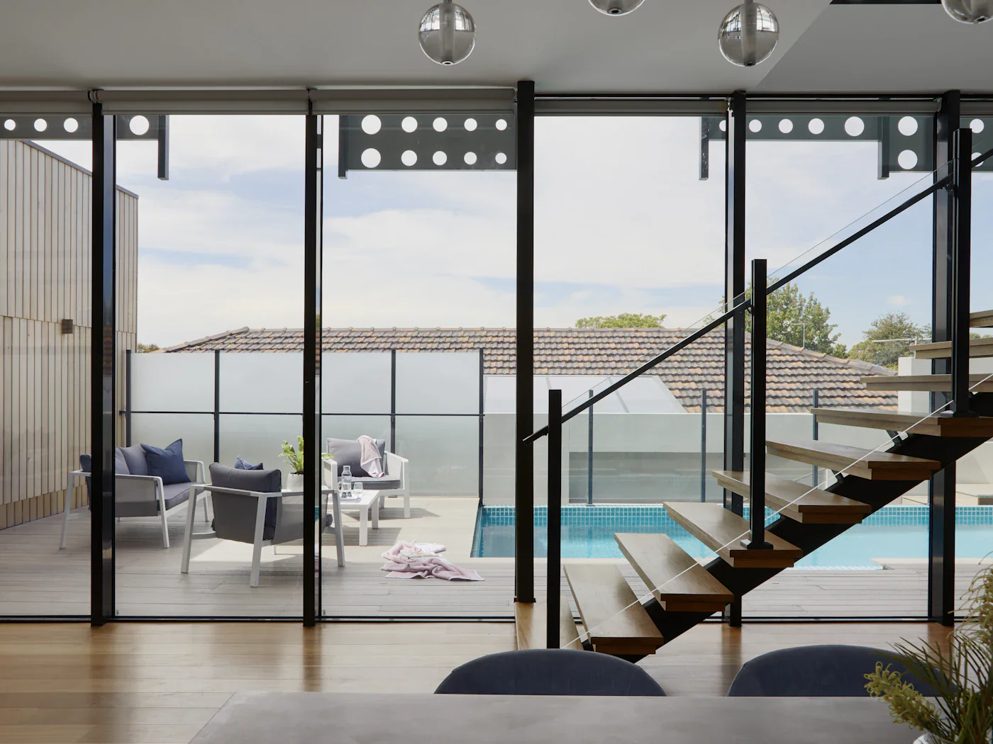 Glass doors folded back onto the pool deck, stair rail beyond