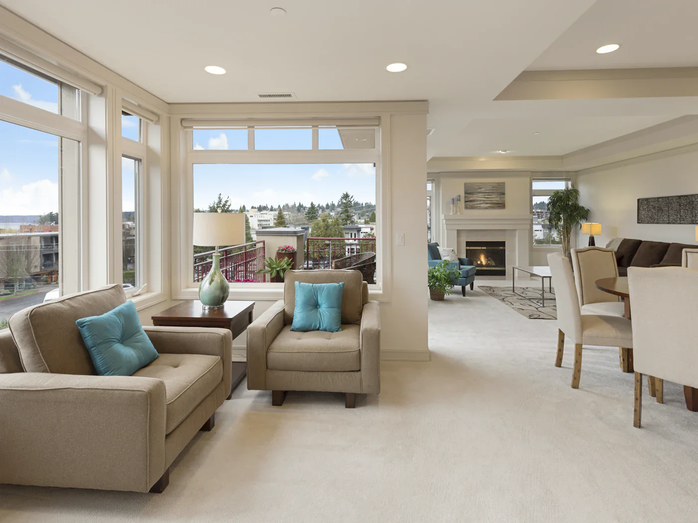 Open living and dining space with a fireplace and teal armchairs