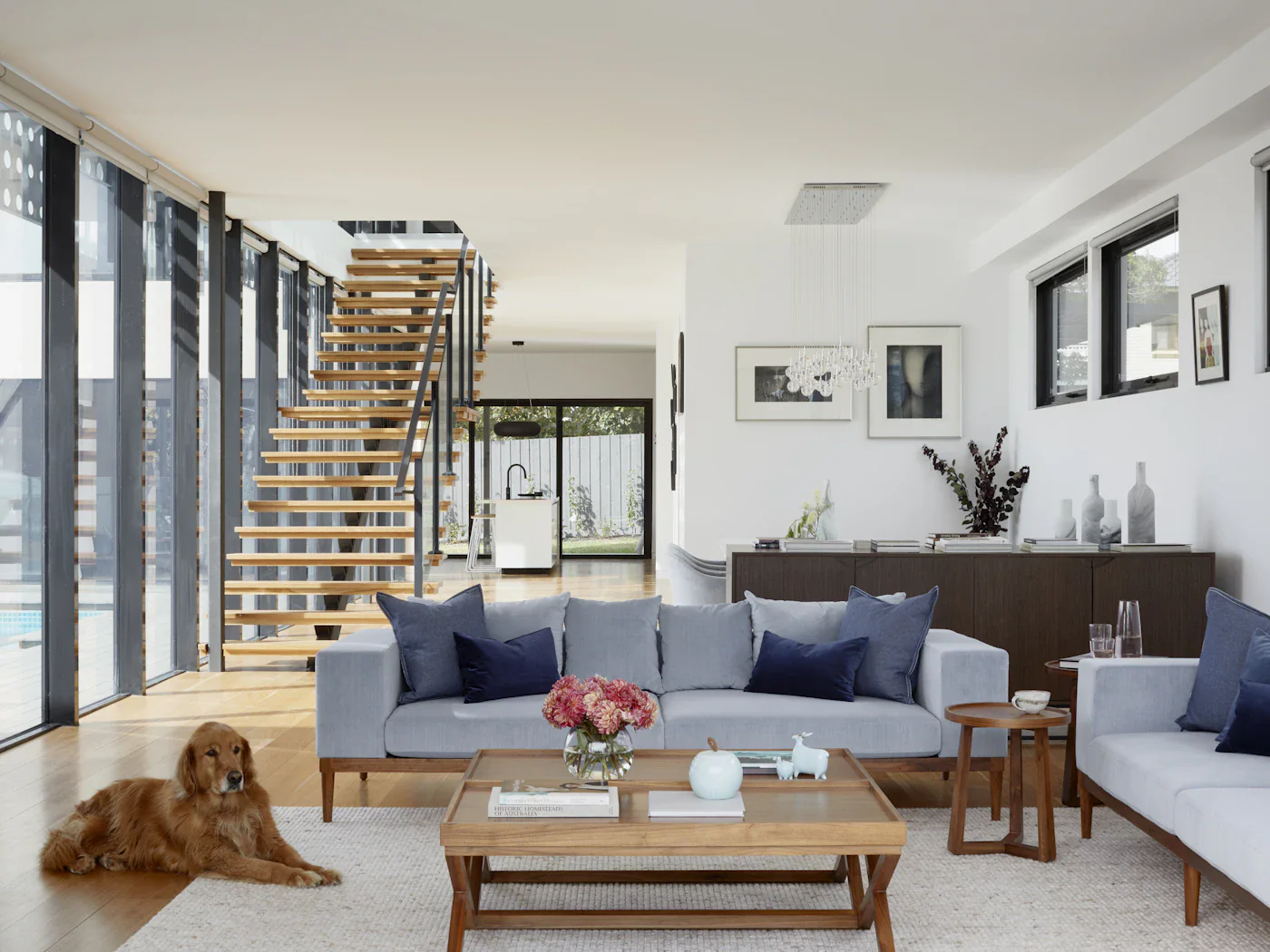 Living room with an open timber staircase and windows on two sides